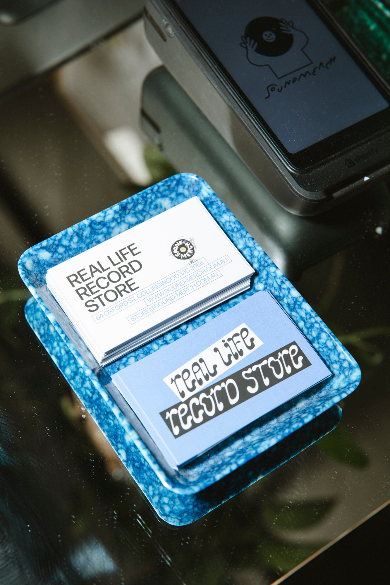 Small rectangular object with 'Real Life Record Store' text on a reflective surface